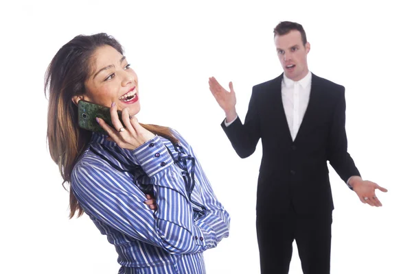 Young woman talks into mobile phone while boss looks from behind — Stock Photo, Image