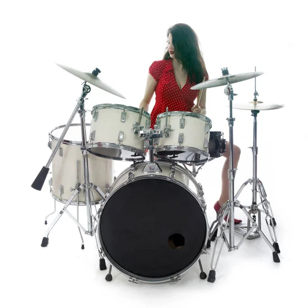 Sexy brunette in red dress plays drum kit in studio — Stock Photo, Image