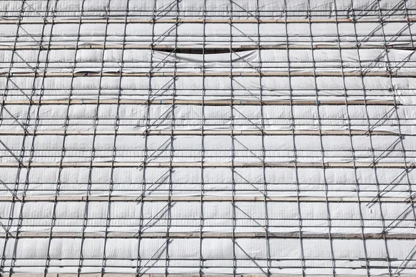 Gevel van het witte doek op steigers van hoge nieuwbouw — Stockfoto
