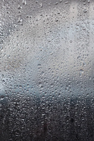 Raindrops on window of car and background in shades of blue — Stock Photo, Image