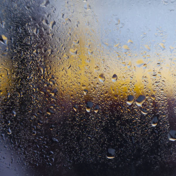 Raindrops on window of car and yellow blue background — Stock Photo, Image
