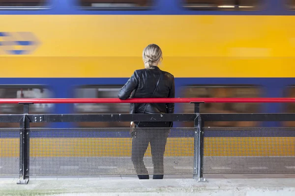 young woman waits on platform of railway station in holland whil