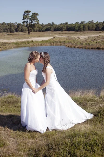 Juste marié heureux lesbienne couple en robe blanche près de petit lac — Photo