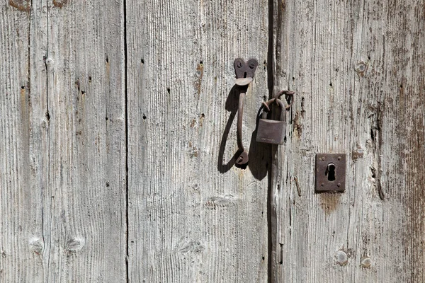 Padlock and handle on grungy old wooden door with hardly any pai — Stock Photo, Image