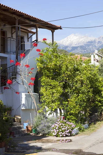 Casa com flores vermelhas e céu azul no dia ensolarado da primavera em grego — Fotografia de Stock