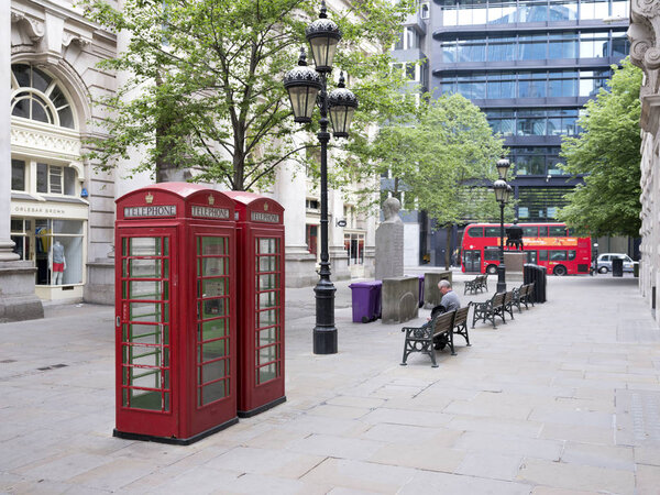 red telephone booths on square in the city of London while red b