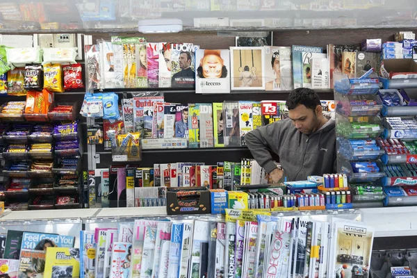 Verkäufer von Zeitungen und Zeitschriften liest, während er auf die Verwahrung wartet — Stockfoto