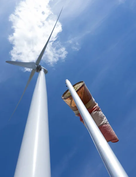 Turbina eólica e windbag como silhueta contra o céu azul — Fotografia de Stock