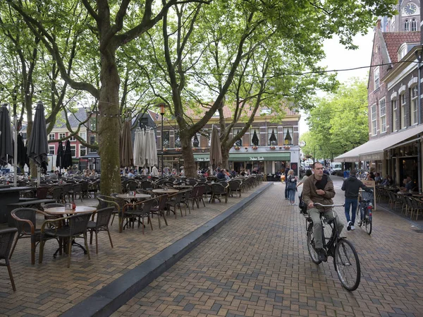Люди на открытом кафе в центре старого голландского города Делфт в — стоковое фото