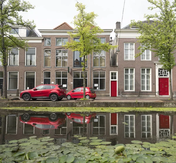Voitures rouges et portes le long du canal plein de nénuphars en remorquage hollandais — Photo