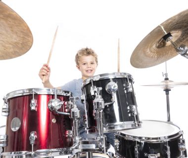 Genç beyaz çocuk bateri çalıyor studio karşı beyaz backgrou