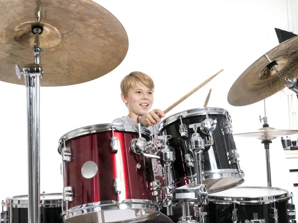 Jovem adolescente menino toca a bateria no estúdio contra branco backgroun — Fotografia de Stock