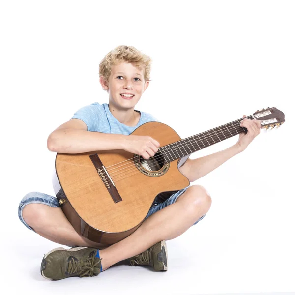 Ξανθιά Έφηβος αγόρι με κιθάρα στο στούντιο ενάντια σε λευκό φόντο — Φωτογραφία Αρχείου
