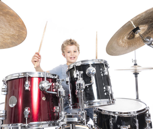 young caucasian boy plays drums in studio against white backgrou