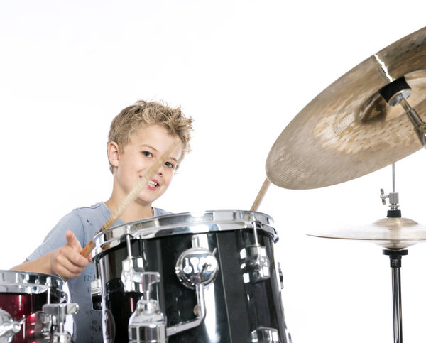 Молодой кавказский мальчик играет на барабанах в студии против белой бэкгру
