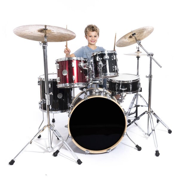 young caucasian boy plays drums in studio against white backgrou