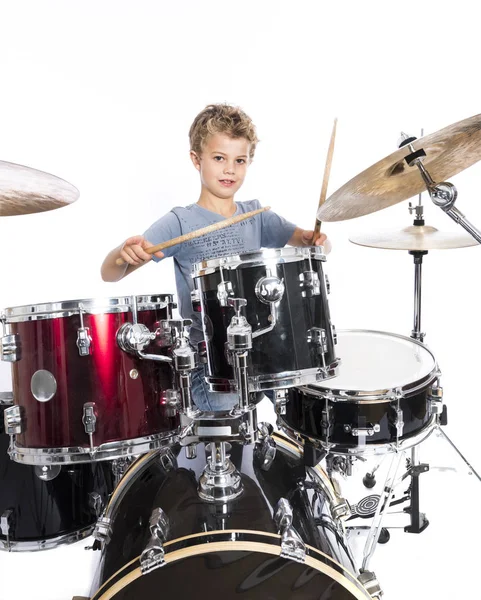 Young caucasian boy plays drums in studio against white backgrou — Stock Photo, Image