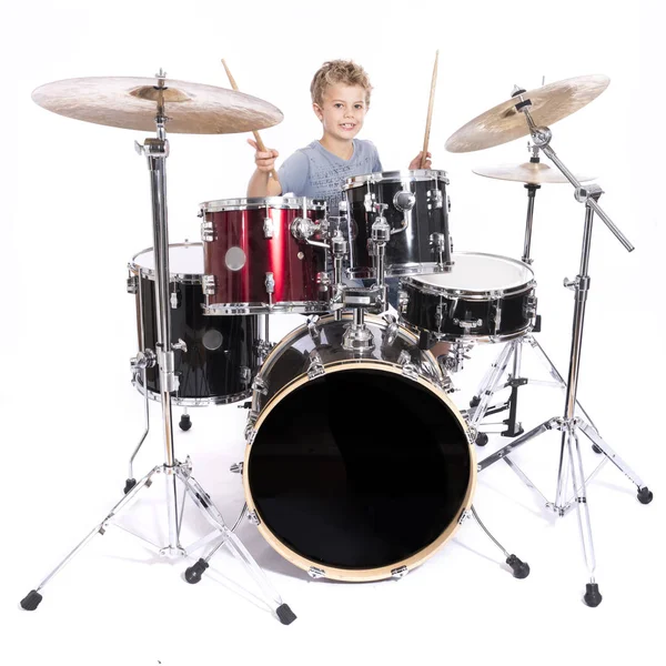 Young caucasian boy plays drums in studio against white backgrou — Stock Photo, Image