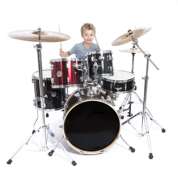 Young caucasian boy plays drums in studio against white backgrou — Stock Photo, Image