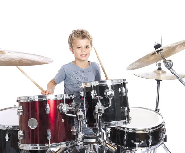 Young caucasian boy plays drums in studio against white backgrou — Stock Photo, Image