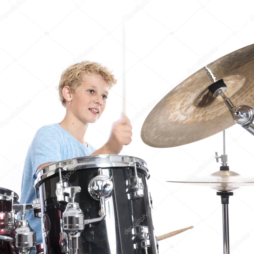 blond teen boy plays drums at drumkit in studio against white ba