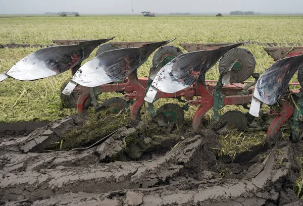 Tierra recién arada y tractor con arado — Foto de Stock