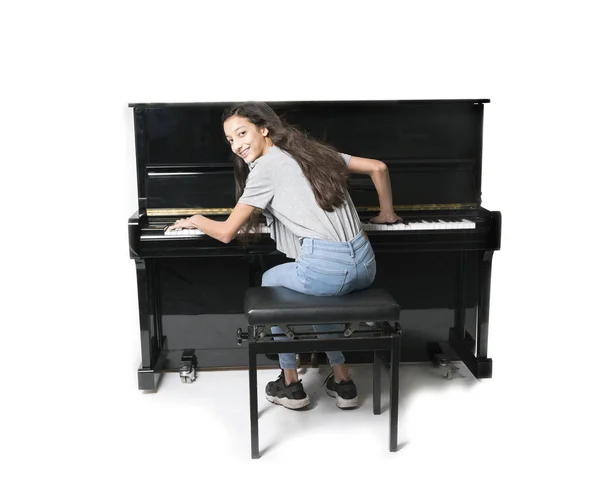 Dospívající brunetka a černé pianino ve studiu — Stock fotografie