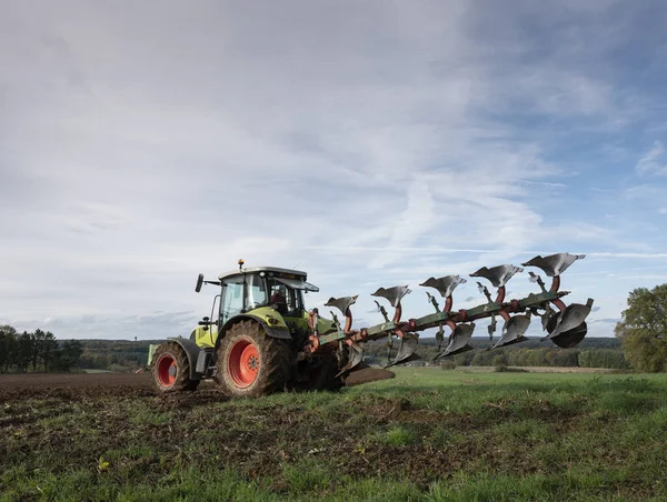 Traktor a pluh pod modrou oblohou na poli v luxembourgh — Stock fotografie