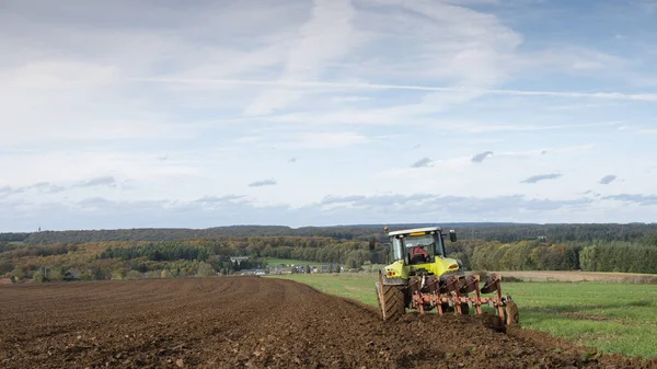 Trator e arado sob céu azul no campo em luxembourgh — Fotografia de Stock