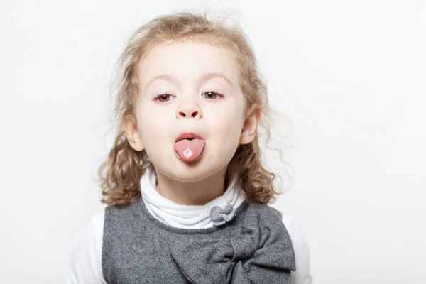 Malá kudrnatá holka ukazuje jazyk — Stock fotografie