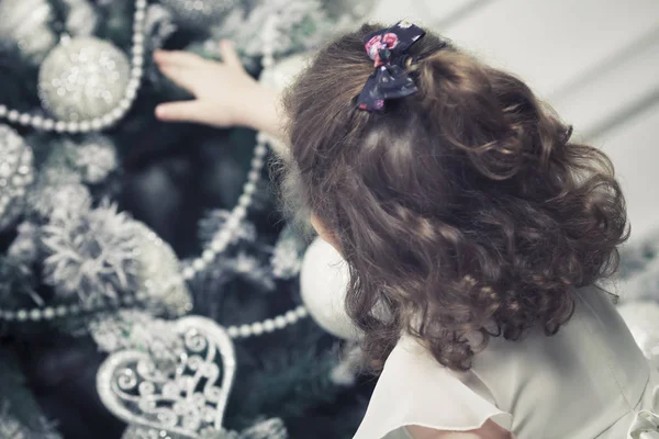 Little Curly Girl Reaches Out Christmas Tree — Stock Photo, Image