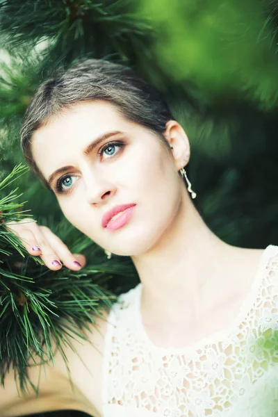 Young beautiful woman with short haircut in fir branches