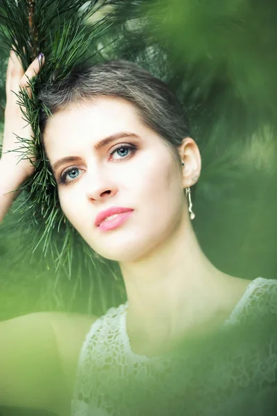 Young beautiful woman with short haircut in fir branches