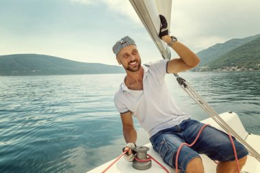 Bir yelkenli yat üzerinde şapkalı bir adam