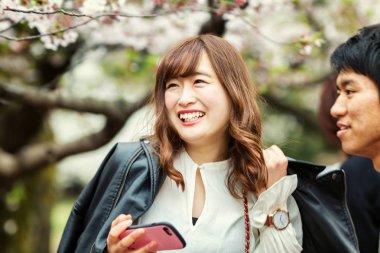 Mutlu çift kiraz çiçeklenme ile bir parkta çiçekleri