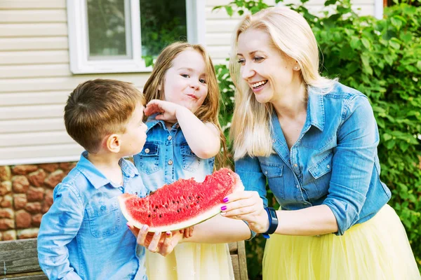 Junge Familie isst Wassermelone im Hof des Hauses — Stockfoto
