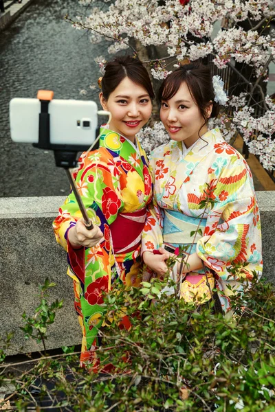 Chicas hermosas felices en un parque con flores de cerezo en flor — Foto de Stock