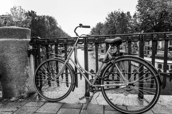 Bicicleta en un puente del canal en Amsterdam. Primer plano. Blanco y negro . Imágenes De Stock Sin Royalties Gratis