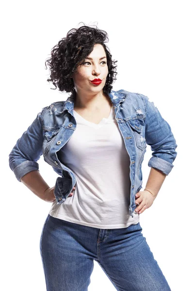 Jeune femme sexy plus la taille en jeans. Brune lumineuse aux cheveux bouclés et aux lèvres rouges. Isolé sur fond blanc . — Photo