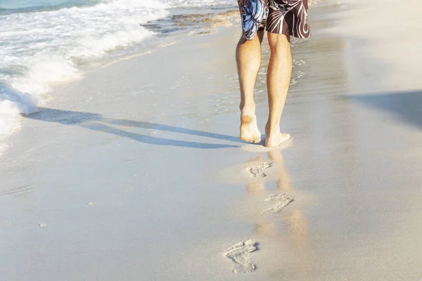 Rastros de pies masculinos en la playa de arena del mar en un día soleado . — Foto de Stock