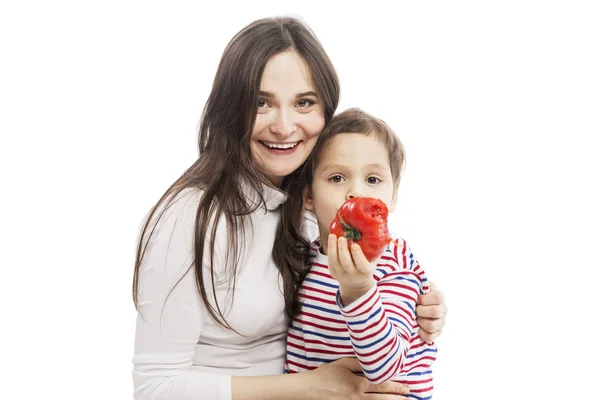 Jonge lachende moeder met een zoon zijn vegetariërs. De jongen eet een sappige tomaat. Geïsoleerd over witte achtergrond. — Stockfoto