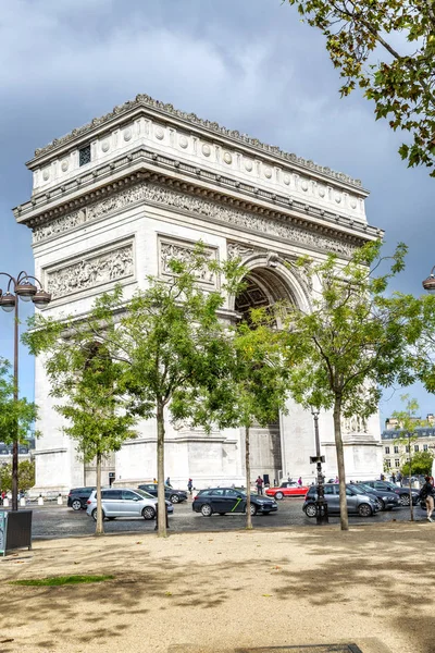 Párizs, Franciaország, 2019.10.09: A Diadalív a fák zöldjében a kék ég ellen egy napsütéses napon. Oldalnézet. — Stock Fotó