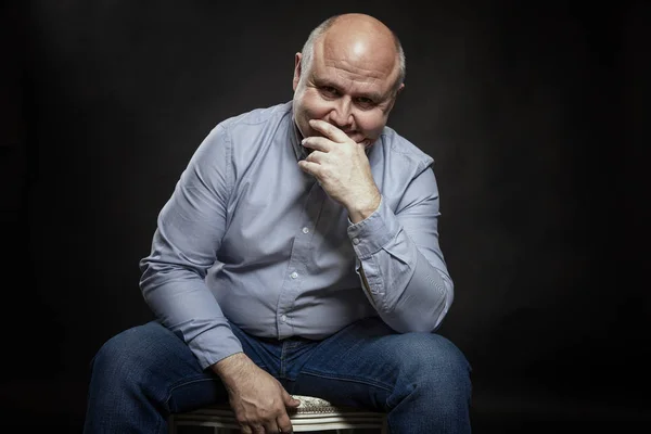 Sorrindo careca homem de meia-idade em um fundo preto . — Fotografia de Stock