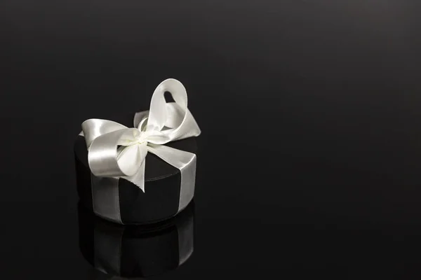 Круглый черный подарочный коробок с белым бантом на черном фоне. Открытка. Пространство для текста . — стоковое фото