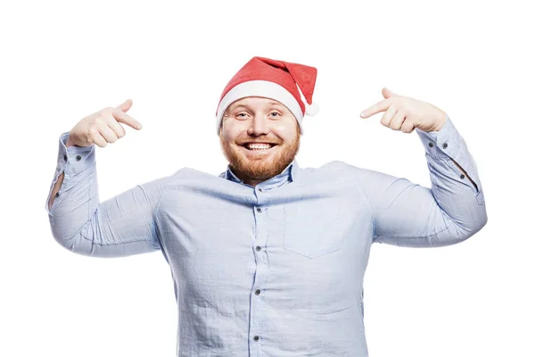 Glimlachende roodharige man met een baard in een blauw shirt en in een kerstmuts. Een close-up. Geïsoleerd over witte achtergrond. — Stockfoto