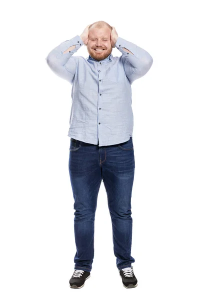 Um homem rindo com uma barba vermelha em jeans e uma camisa azul está segurando sua cabeça em suas mãos. Altura total. Isolado sobre fundo branco . — Fotografia de Stock