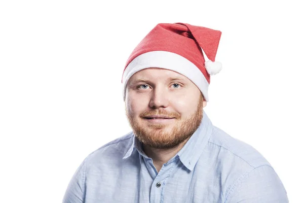 满脸笑容,红头发,留着胡子,身穿蓝色衬衫,头戴圣诞帽. 8.特写。 在白色背景下被隔离. — 图库照片