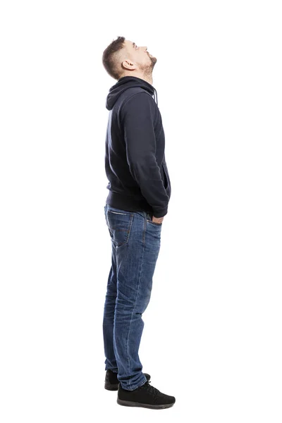 Un bel giovanotto in jeans è in piedi. Mani in tasca. Vista laterale. isolato su sfondo bianco . — Foto Stock