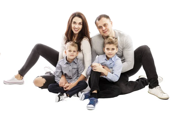 Gelukkige familie met twee zonen zitten op de grond. Geïsoleerd over witte achtergrond. — Stockfoto