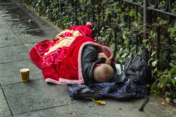 Бездомный спит под одеялом на улице европейского города
.